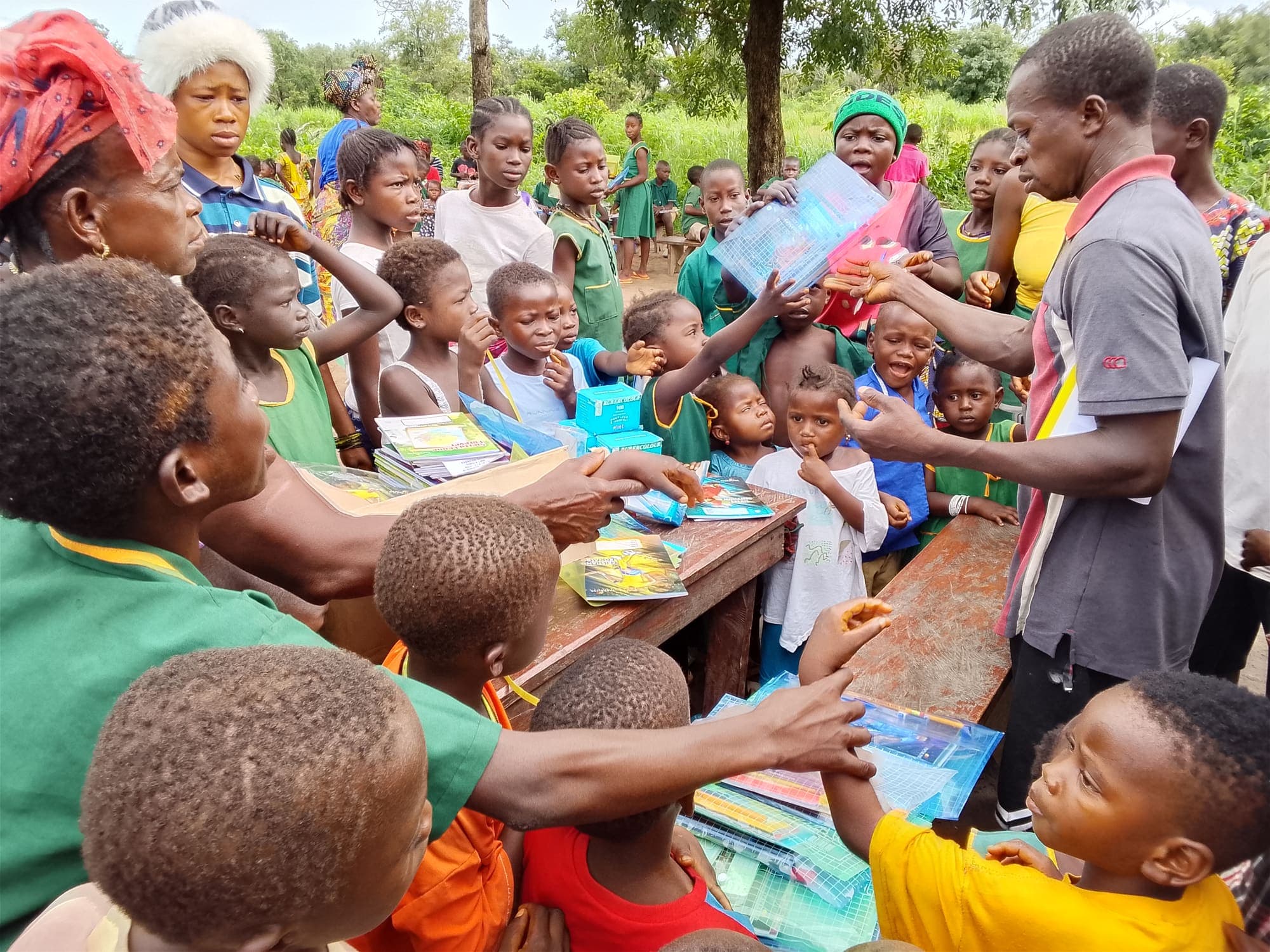 Children and adults gathered around a table of school supplies during a distribution in a rural community.